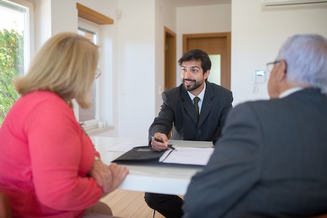 person in black suit interview two prospective tenants and review document with them